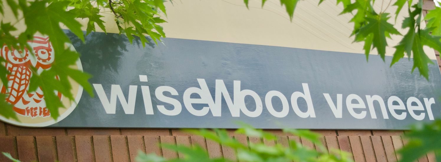 WiseWood wood veneer company sign with owl logo and wordmark.