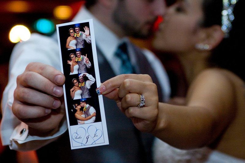 Couple kissing behind their photo booth image print out.