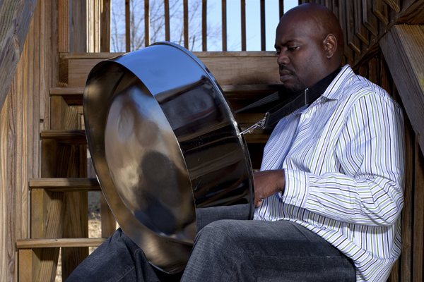 A steel pan drummer playing softly on a staircase.