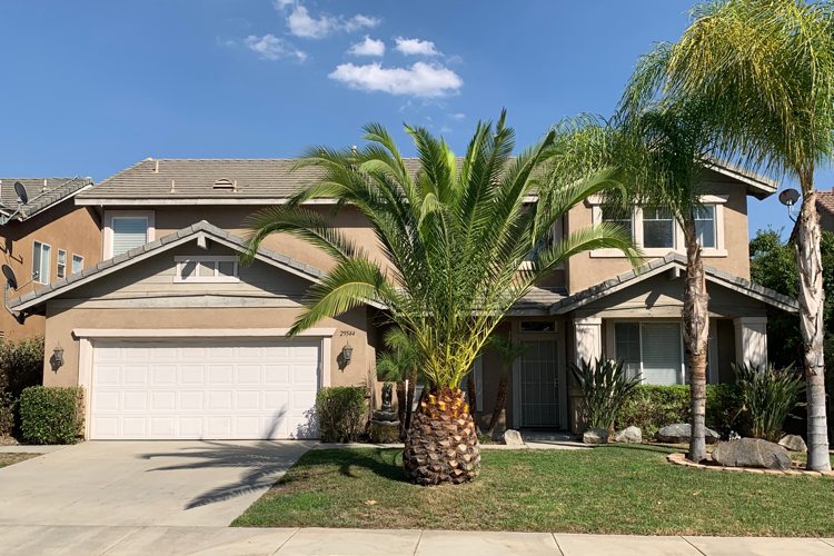 exterior of 29544 Wagon Creek; two-story beige stucco home with large palm tree