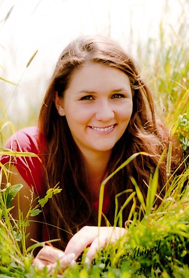 smiling young woman peeking out from tall grasses