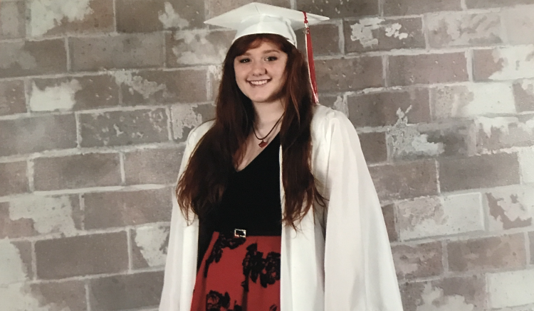 smiling young woman in white cap and gown