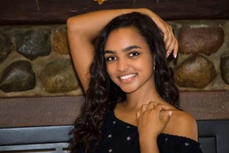smiling young woman posing with arm around her head