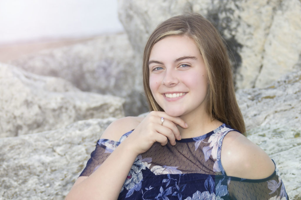 smiling young woman posing on large rocks