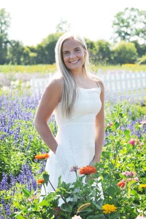 smiling young woman in white dress in field of flowers