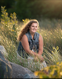 smiling young woman sitting around ornamental grasses