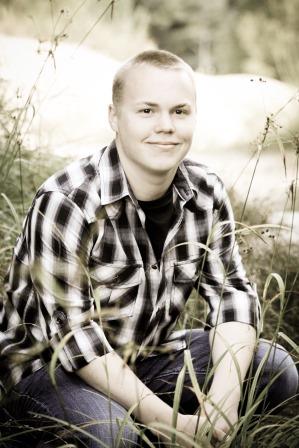 young man in flannel shirt sitting in ornamental grasses