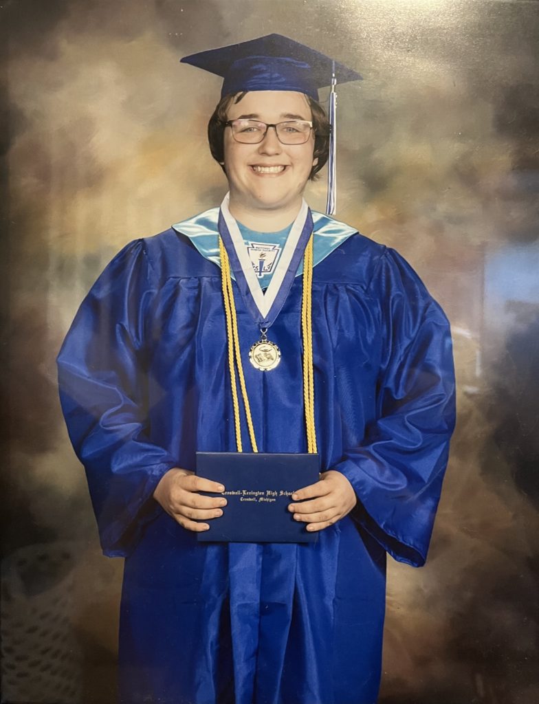 young person in blue cap and gown holding diploma