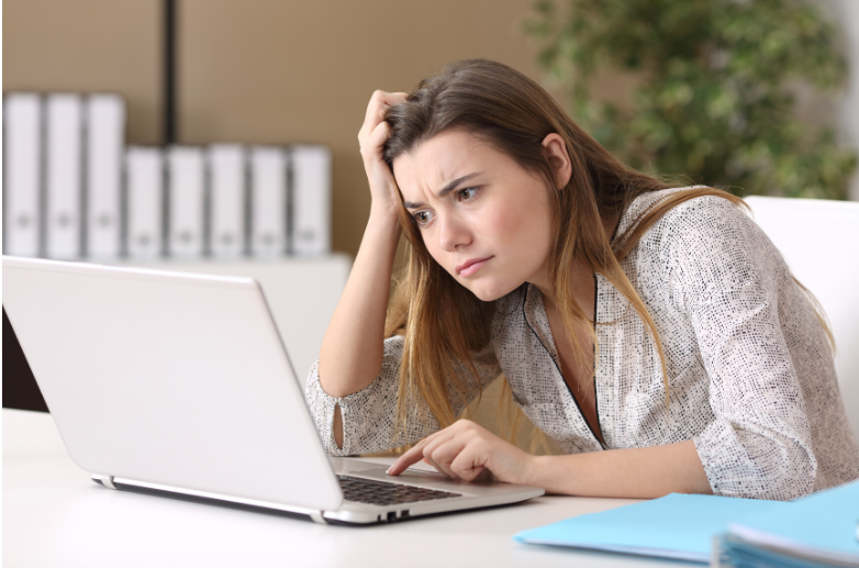 young woman sitting and researching scoliosis treatment alternatives on a laptop while looking confused